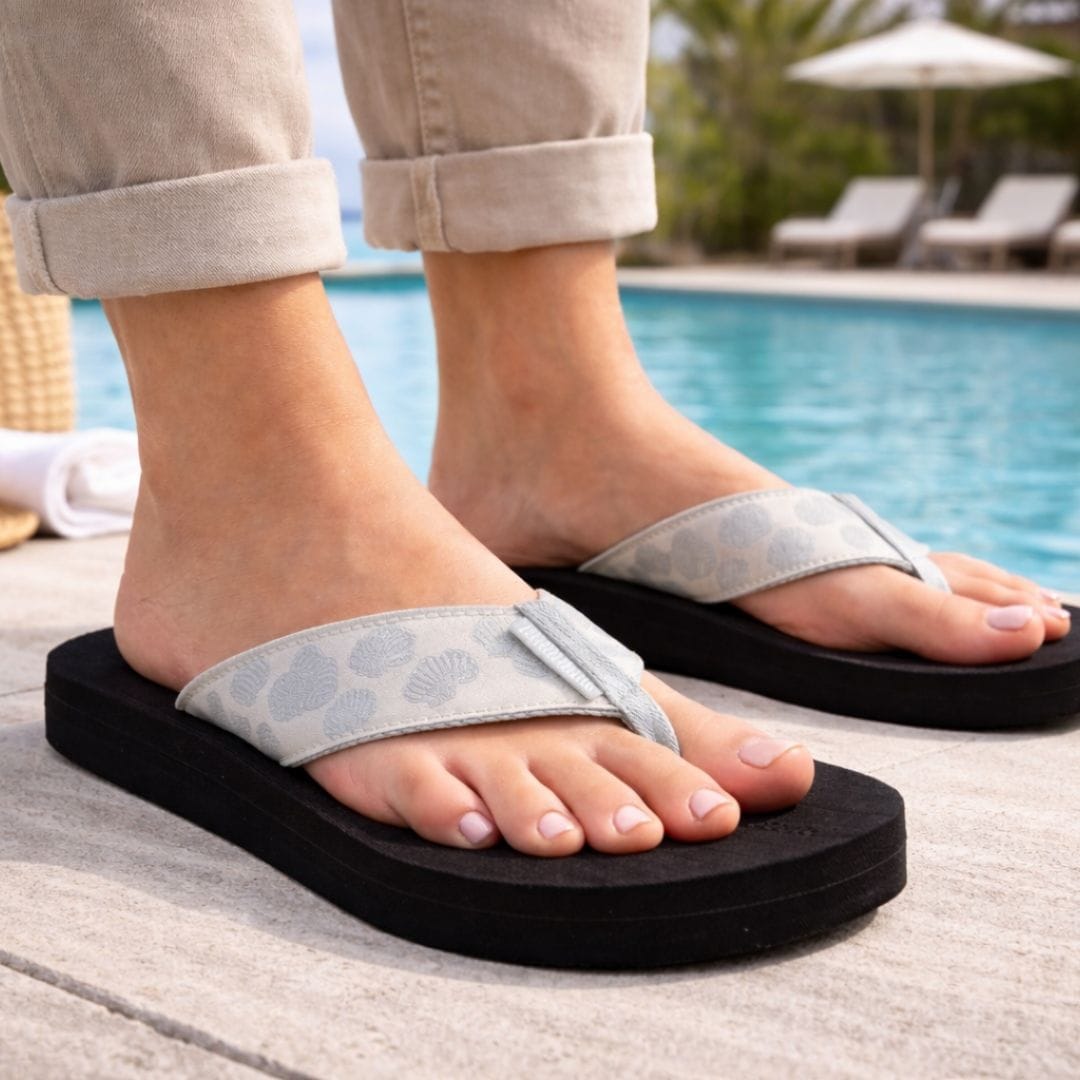 Person wearing black and gray sandals by a poolside